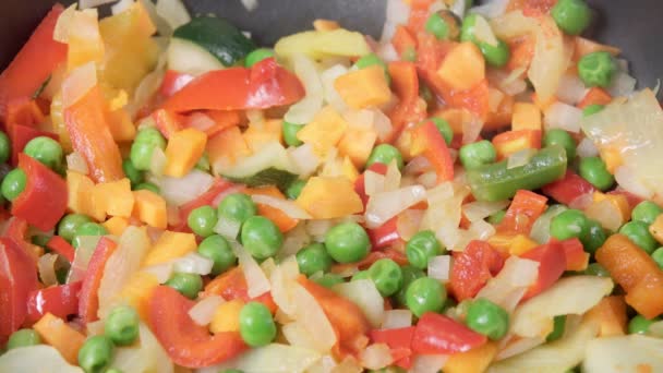 Cottura stufato di verdure primo piano. piselli, peperoni, cipolle, carote in una padella — Video Stock