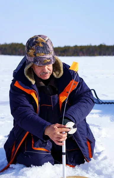 氷釣りだ 森と青空を背景に冬の湖で漁をしている漁師は — ストック写真