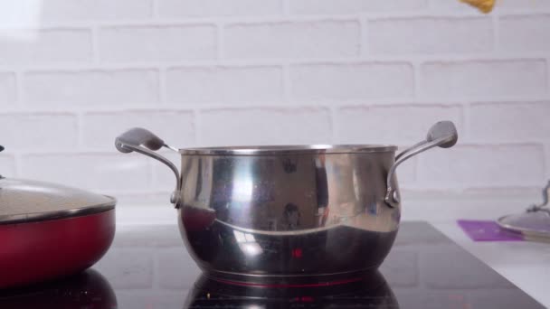 Keittämällä spagettia keittiössä, käsi laittaa pastaa kuumaan veteen. valikoiva kohdentaminen — kuvapankkivideo