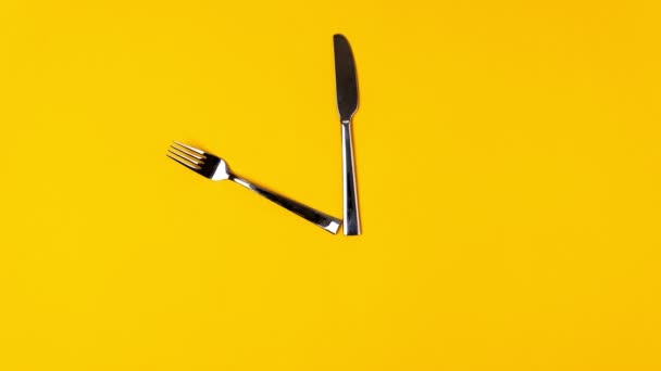 Tempo di mangiare, coltello da forchetta, sveglia su sfondo giallo. Arresto animazione movimento, vista dall'alto — Video Stock