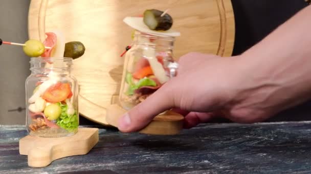 Jarcuterie Snacks en tarros transparentes queso jamón aceitunas lechuga pepinos nueces. — Vídeo de stock