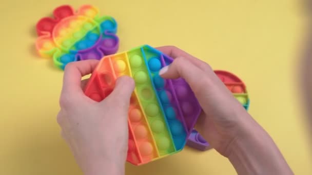 Mädchenhände drücken auf das Anti-Stress-Spielzeug Pop it auf gelbem Hintergrund. Selektiver Fokus — Stockvideo