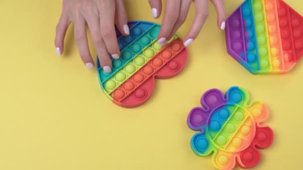 Mädchenhände drücken auf das Anti-Stress-Spielzeug Pop it. Draufsicht auf gelbem Hintergrund — Stockvideo