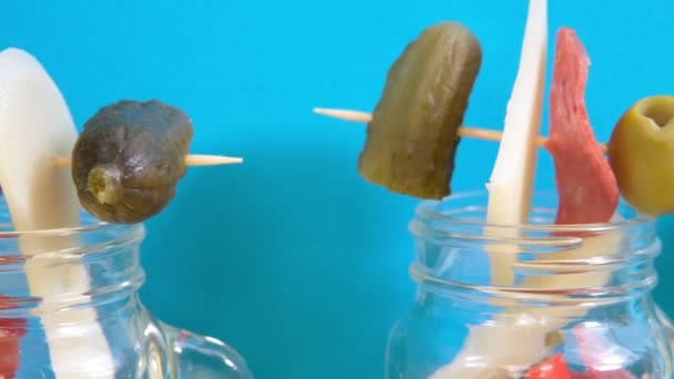 Snacks dans des bocaux transparents Jarcuterie fromage jambon salade concombre noix sur un fond coloré — Video