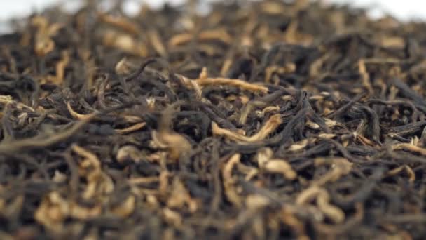 Montón de té negro sobre un fondo blanco. Hojas secas de té negro, deliciosas, naturales. — Vídeo de stock