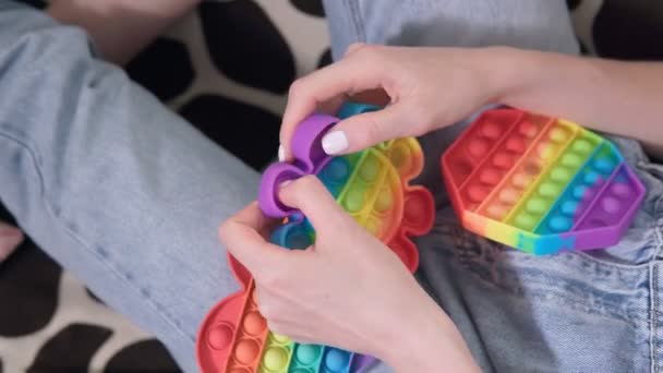 Chica juega con colorido arco iris pop it toy. Enfoque selectivo — Vídeo de stock