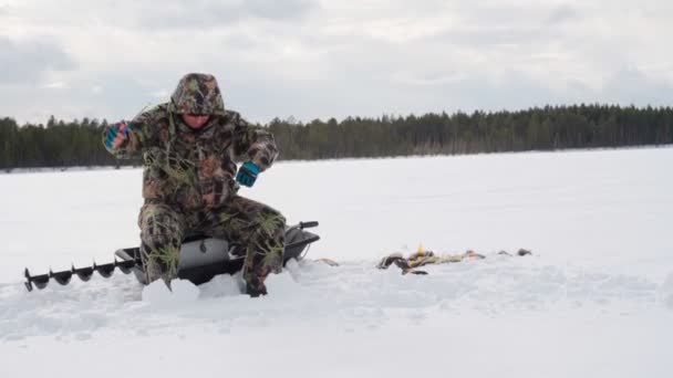Pesca sul ghiaccio un uomo cattura il pesce in inverno sul lago. pesca persico — Video Stock