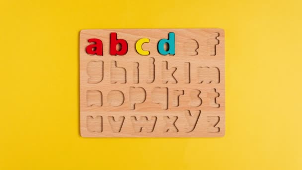 Buchstaben des englischen Alphabets auf gelbem Hintergrund von oben. Stop-Motion-Animation. Selektiver Fokus — Stockvideo