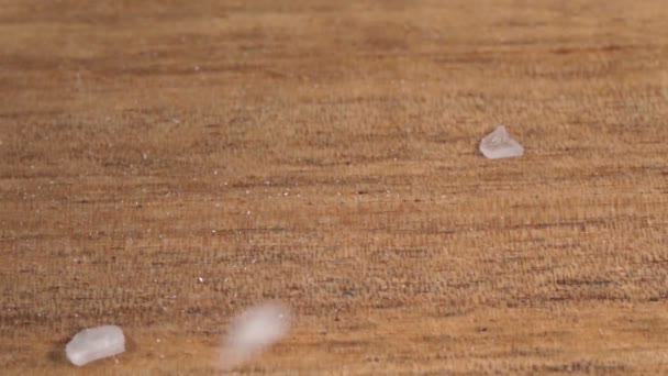 Le sel de mer tombe sur une surface en bois, gros plan, macro. Mouvement lent — Video