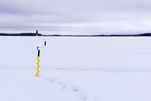 ice drill in the snow on a winter lake. winter sports winter fishing. space for copying text