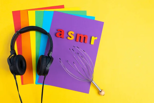 Аудио исцеление, буквы ASMR наушники, вид сверху, разноцветный фон. Копирование пространства — стоковое фото