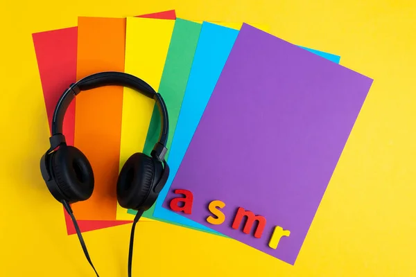 Аудио исцеление, буквы ASMR наушники, вид сверху, разноцветный фон — стоковое фото