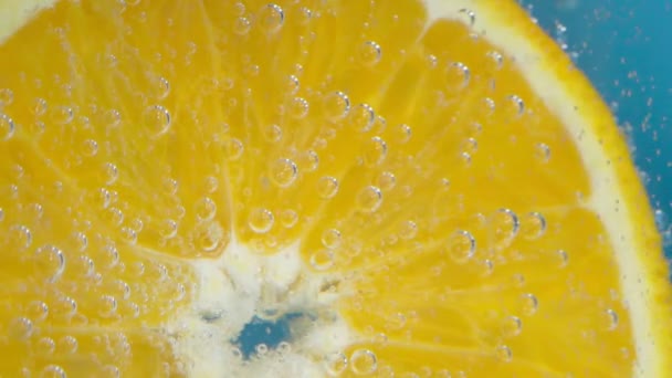 Pomerančové ovoce ve vodě zblízka makro. Osvěžující grapefruitový nápoj, koktejl. Zpomalený pohyb — Stock video