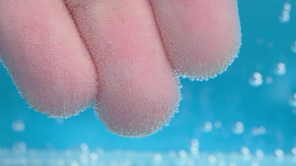 Una mano de hombre bajo el agua. Agua azul brillante con burbujas de aire. Macro, enfoque selectivo — Vídeo de stock