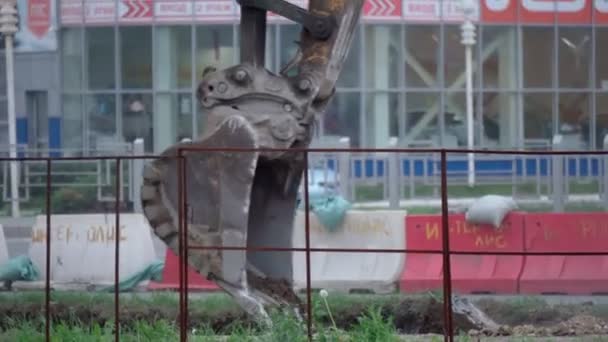 Vykopávač vykopává zem, výstavba silnic ve městě. Selektivní zaměření — Stock video