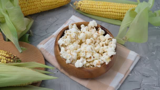 Saboroso pipoca tradicional e espigas de milho no fundo cinza — Vídeo de Stock