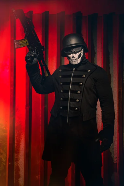 Опасный человек в маске с винтовкой на красном фоне — стоковое фото