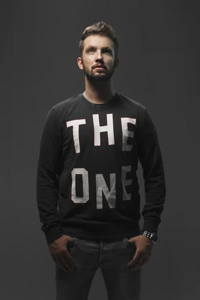 Young strong slim man in t-shirt posing on gray background. — Stock Photo, Image