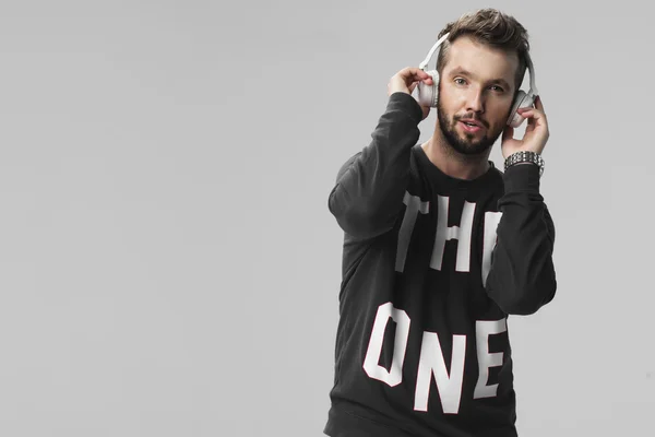 Portrait of a handsome young man listening music against a grey background — Stock Photo, Image