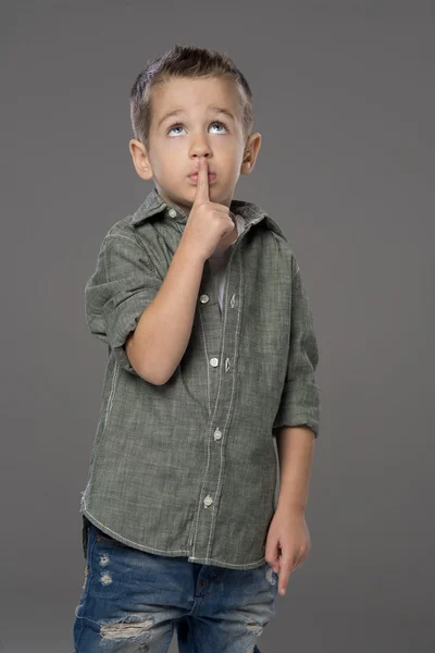 Retrato de estudio de un niño haciendo un gesto de silencio, fondo gris — Foto de Stock