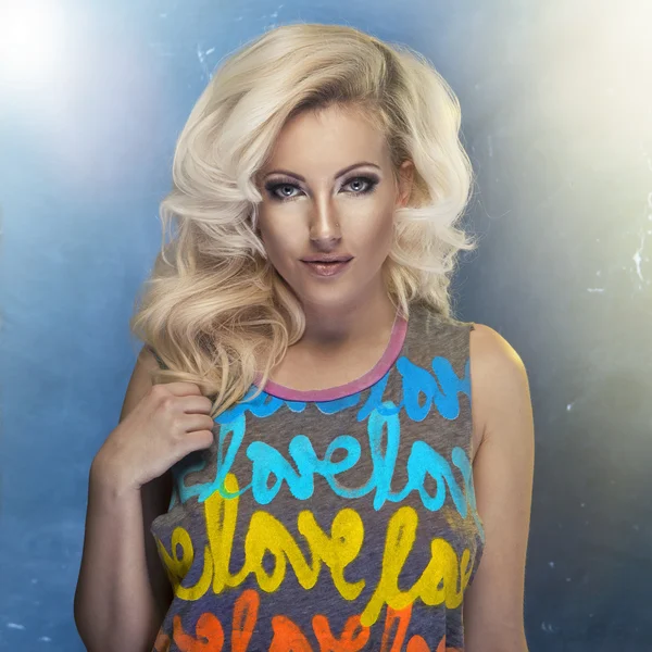De blonde vrouw schoonheid met krullend haar en kleurrijk T-shirt — Stockfoto