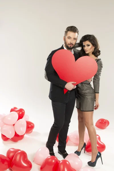 Young smiling caucasian couple holding sign in form of red heart — Stock Photo, Image