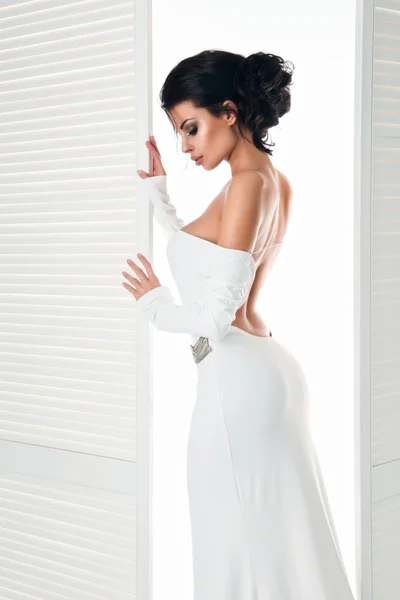 Mooie vrouw in de witte jurk naast de deur — Stockfoto