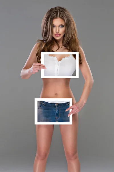 Bela jovem sexy nu mulher segurando roupas no branco bordo — Fotografia de Stock