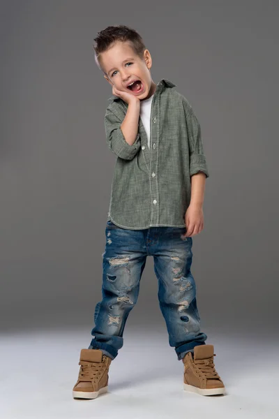 Casual menino com sorriso sobre um fundo cinza — Fotografia de Stock