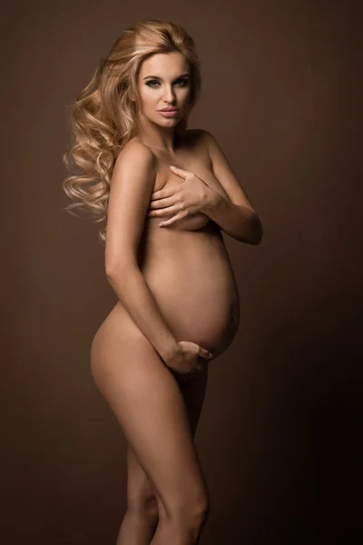Undressed pregnant woman covering her breast — Stock Photo, Image