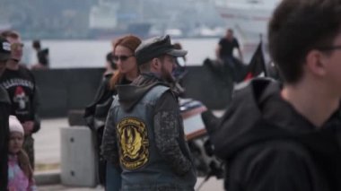 Vladivostok, Primorsky Bölgesi, Rusya - 24 Nisan 2021: Motosiklet kulübü ejderhalarından kep ve yelek giyen bir adam kalabalığın arasında yürür ve etrafa bakar