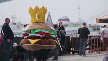 Vladivostok, Primorsky Bölgesi, Rusya - 24 Nisan 2021: Burger kostümlü bir adam elinde bayrakla bir burger kralının reklamını yapıyor.