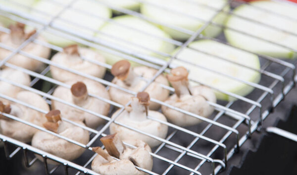 Овощи поджариваются на вешалке на железном гриле. Перец, цуккини, грибы. Улица, день.