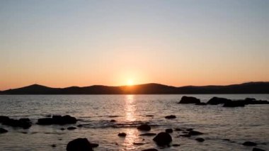 Sıcak bir yaz akşamı, Mora kıyılarında boğaz boyunca, güneş neredeyse dağların arkasında batıyordu, yakın kıyılarda bir sürü taş var.