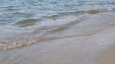 Ağır çekim, kumlu sahilde dalgalar akıyor, güneşli ve güneşli bir gün.