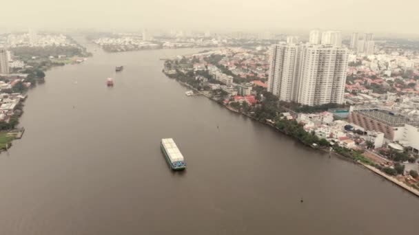 Drone aeriene zbor de drone vreme tulbure cu vedere la râu cu nave container pe fundalul frumoaselor clădiri mari și frumoase ale orașului, cu mașini și motociclete care trec . — Videoclip de stoc