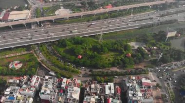 Güneşli bir sabahın erken saatlerinde şehrin üzerinde insansız hava aracı uçurmak, şehir arabalarından ve motosikletlerden dumanlar, şehrin sokaklarını ve büyük şehir binalarını görmek..