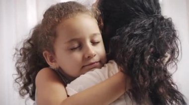 Mutlu küçük çocuk koruyucu anneye sarılıyor gözleri kapalı, sevimli küçük kızı annesine sarılıyor şefkatli anın tadını çıkarıyor..