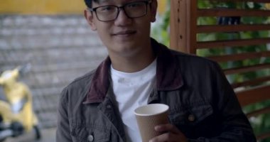Gözlüklü Asyalı bir genç kahve içer..