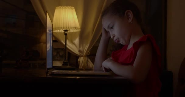 School child, a girl of 7-8 years old, studies at home remotely in the evening, listens to school lectures, does homework, without leaving home. Kids home schooling, kids online education concept. — Stock Video