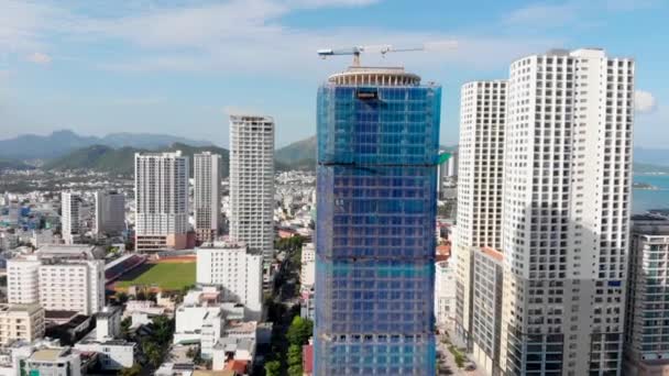 Drone photographie aérienne vous permet d'admirer une belle vue sur la ville et la construction d'un grand bâtiment dans le contexte de beaux gratte-ciel ou la mer bleue. 4K. — Video