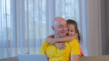 Genç, ciddi, serbest çalışan bir adam evdeki bir kanepede oturuyor, bilgisayarla evde çalışıyor, küçük kızı ona yaklaşıyor ve işinden bıkıyor..