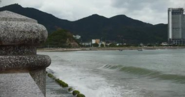 Bulutlu hava, yağmur, büyük gri bulutlar, kasvetli hava, deniz dalgaları bulutlu bir günde şehrin sahilinde kırılıyor..