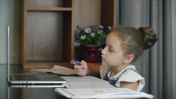 Mała dziewczynka słodkie dziecko w szkole podstawowej 7-8 lat w domu studiuje w nauce rodziny słucha wykładów szkolnych odrabia pracę domową bez wychodzenia z domu.Kształcenie w domu dziecka, koncepcja edukacji dzieci — Wideo stockowe