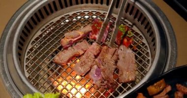 Şef tong 'u kullanıyor ve eti ızgaraya çeviriyor. Ateş yanıyor, yağlı biftek yavaş çekimde pişiyor. Izgara, lezzetli biftek yavaş çekimde yakın çekim..