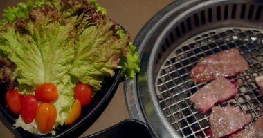 Şef tong 'u kullanıyor ve eti ızgaraya çeviriyor. Ateş yanıyor, yağlı biftek yavaş çekimde pişiyor. Izgara, lezzetli biftek yavaş çekimde yakın çekim..