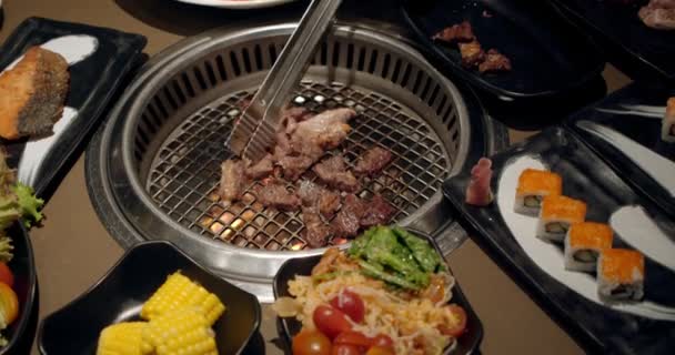 Náčelník používá tanga a otáčí maso na grilu. Oheň hoří, horký šťavnatý olej steak vaří zblízka zpomaleně. Gril, chutné hovězí steak zpomalený film zblízka. — Stock video