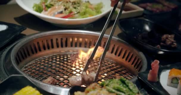 Grill, smaczny befsztyk spowolniony. Szef używa tongu i obraca mięso na grillu. Ogień płonie, gorący soczysty stek olejowy gotowanie zbliżenie slow motion. — Wideo stockowe