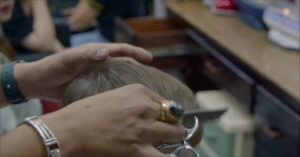 Kinderhaarstyling. Stylist in einer Schutzmaske von covid-19 macht eine stylische Frisur. Kinderfrisur im Salon zur Zeit der Coronavirus-Epidemie. Kleiner Junge bekommt einen Haarschnitt. — Stockvideo