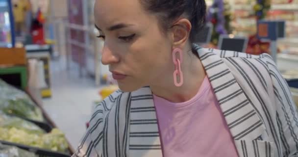 Une jeune femme dans un rayon épicerie d'un supermarché achète de la nourriture, concept où les gens achètent de la nourriture. — Video